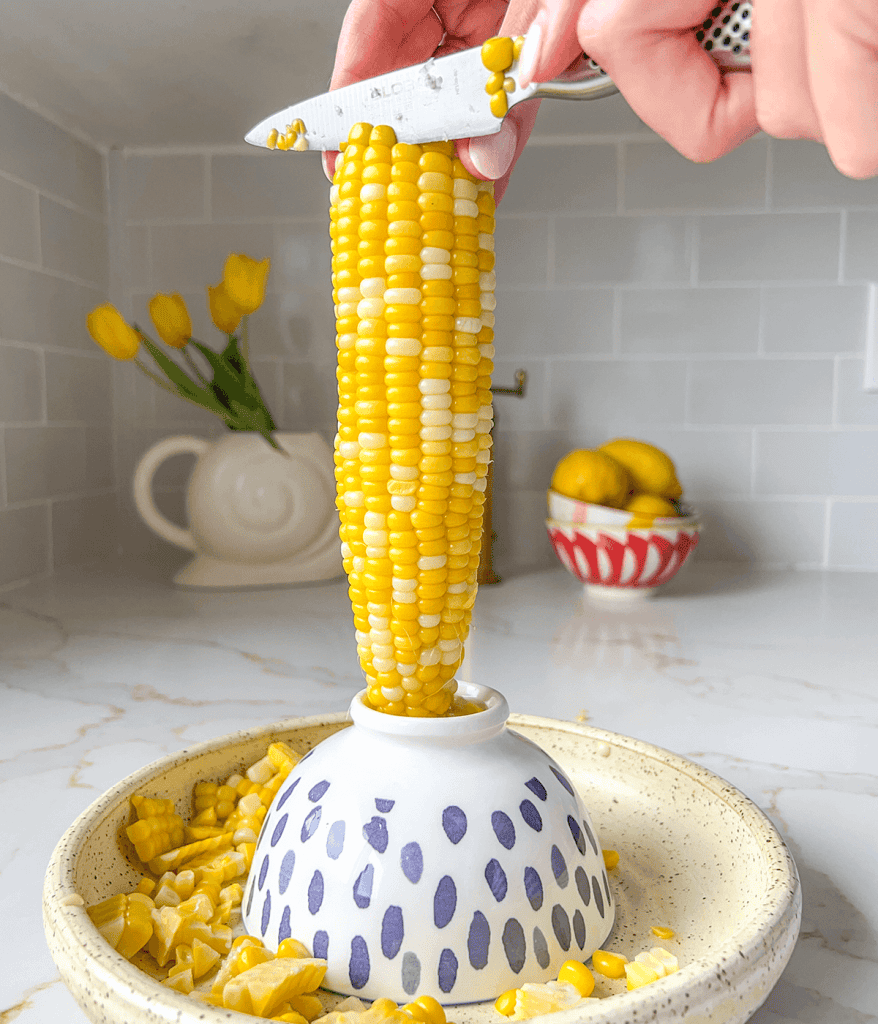 corn being cut off a cob for a pearl couscous salad