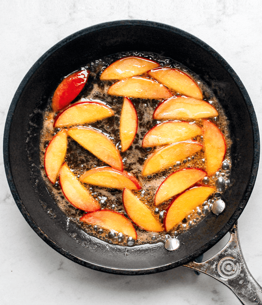 peaches cooking in a pan with hot honey
