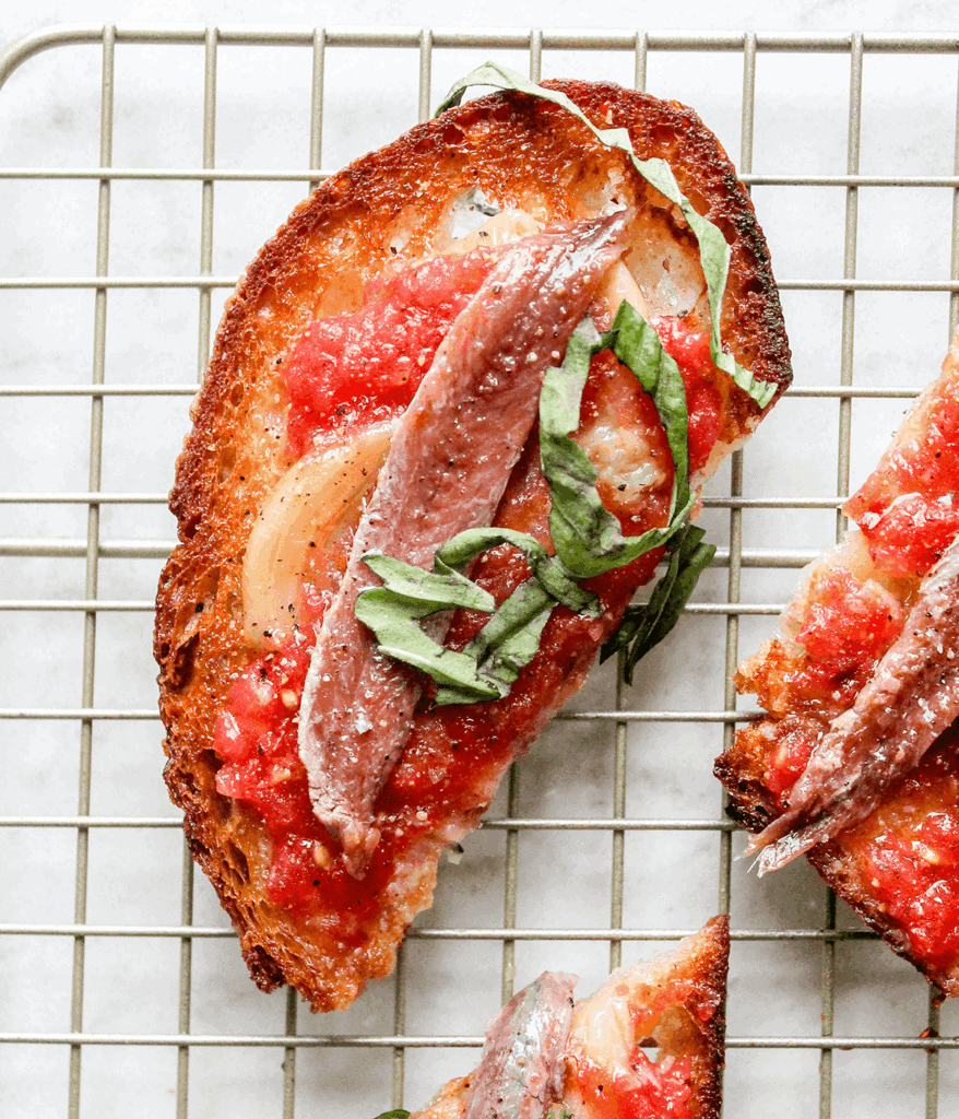 Authentic Pan Con Tomate topped with fresh tomatoes, crispy bread, and savory anchovies. Perfect for.