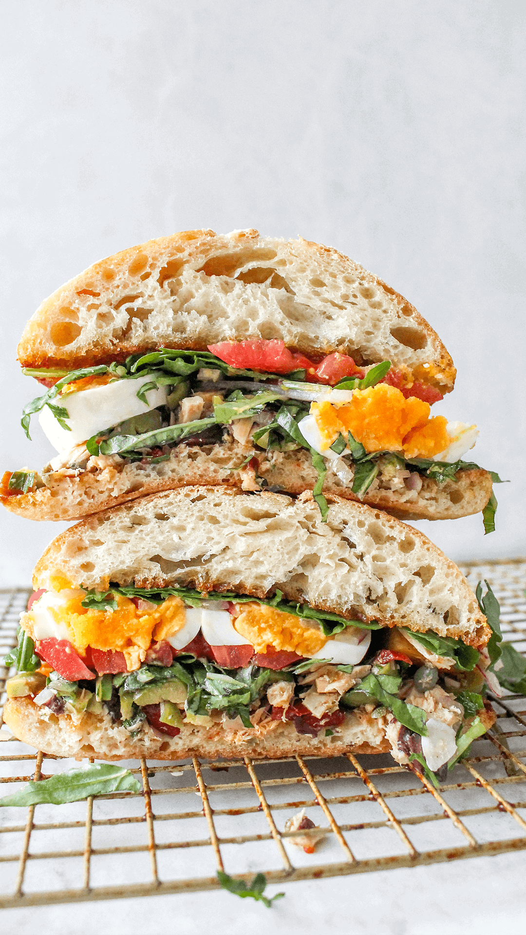 stacked tuna sandwich with jammy eggs and tomatoes