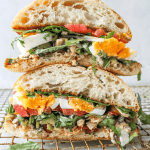 stacked tuna sandwich with jammy eggs and tomatoes