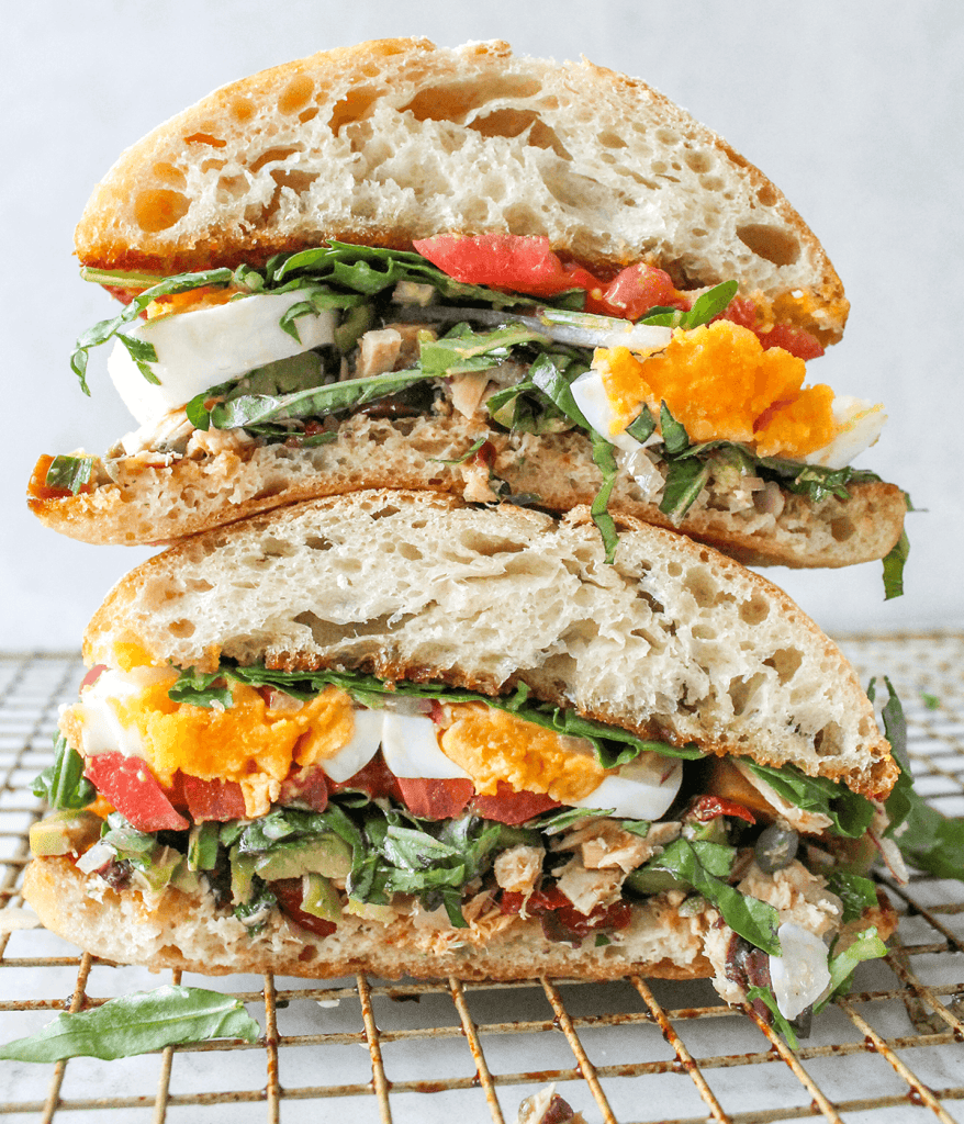 stacked tuna sandwich with jammy eggs and tomatoes