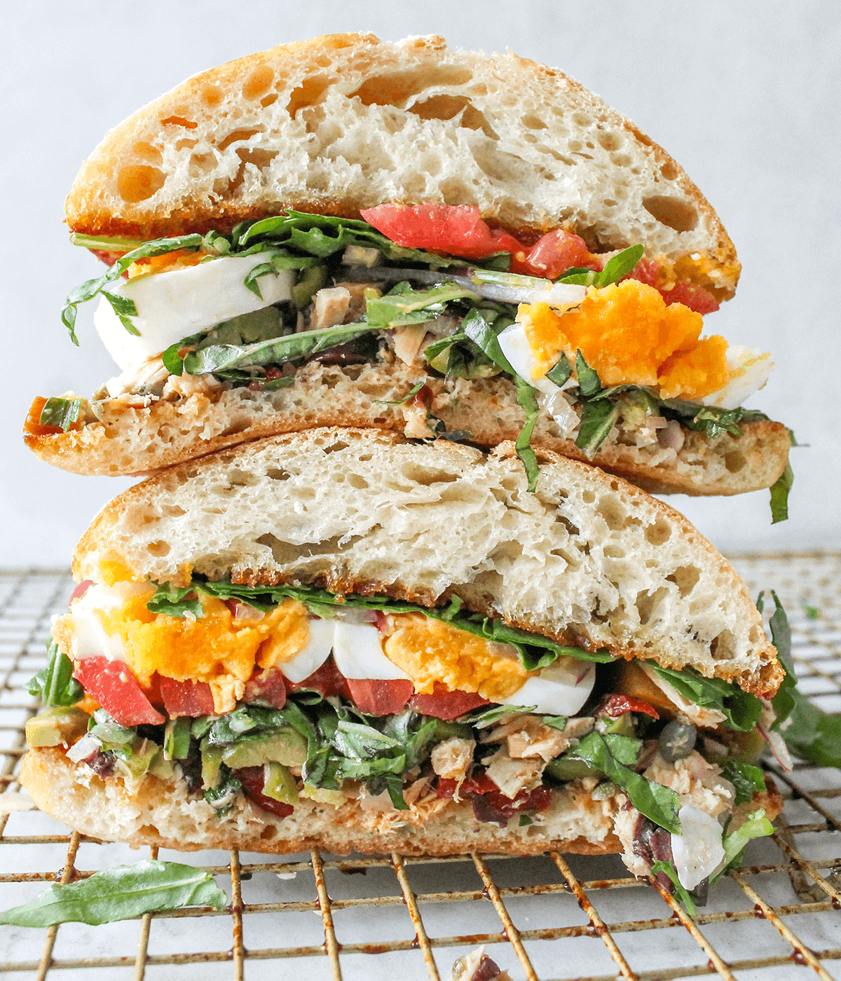 stacked tuna sandwich with jammy eggs and tomatoes