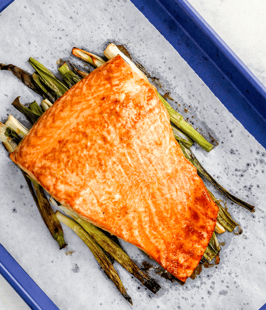 sheet pan photo of salmon over a bed of green onions