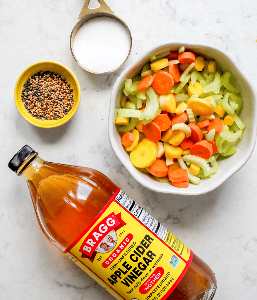 Ingredients for pickled celery and cucumber which includes apple cider vinegar, sugar, and pickling spices.