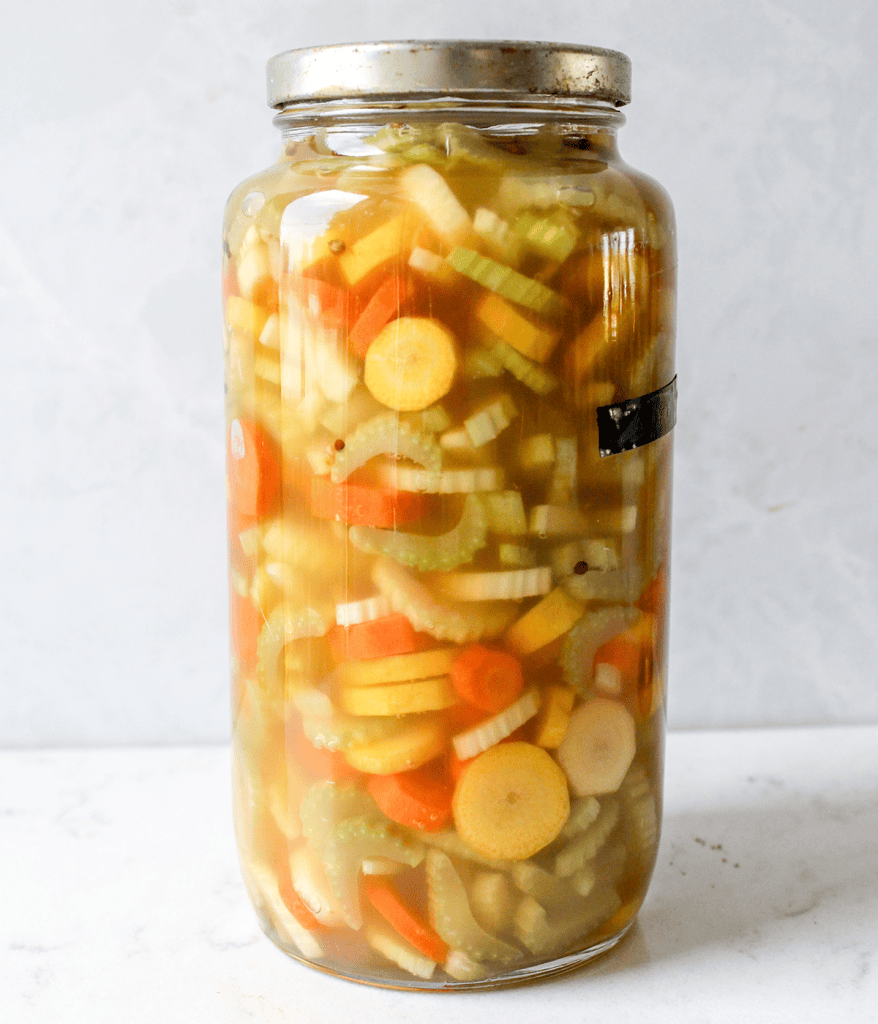 Close-up image of a jar of pickled celery and carrots.
