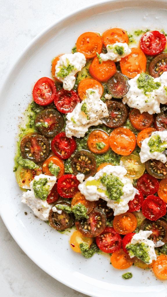 close up of a pesto tomato and burrata plate