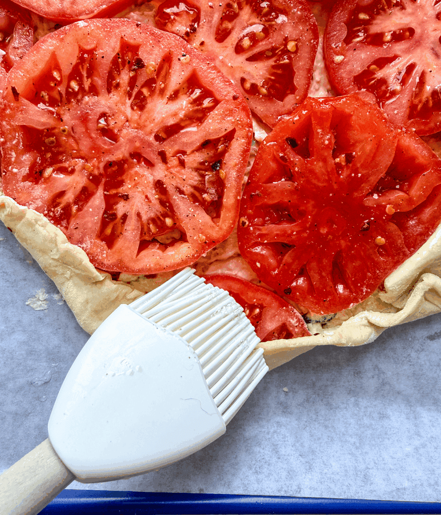 brushing butter on puff pastry tomato tart