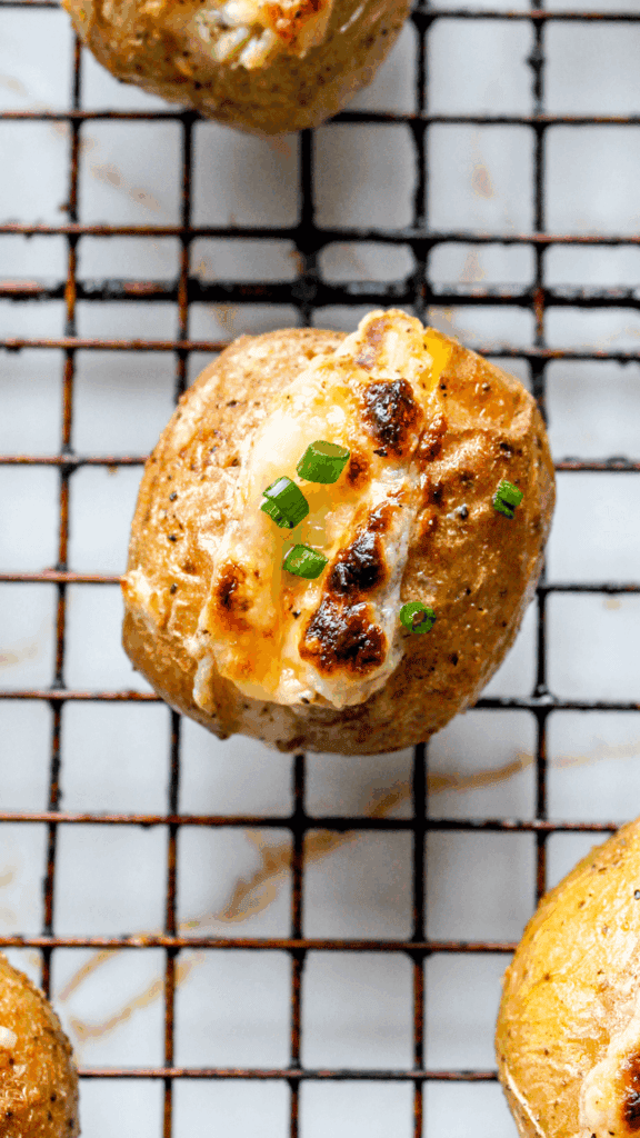 Crispy baked potato topped with melted cheese and green onions, savory snack from Bon Abbetit.