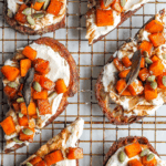 Savory roasted sweet potato toast topped with creamy cheese, sage, and pumpkin seeds, served on a wire rack at bon abbetit.
