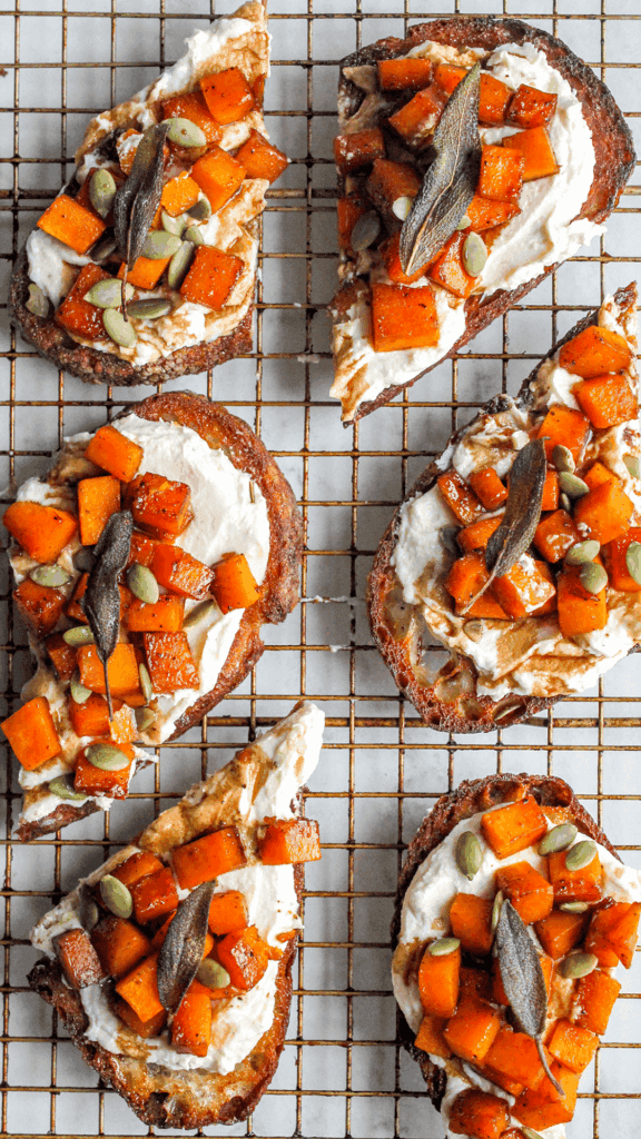 Savory roasted sweet potato toast topped with creamy cheese, sage, and pumpkin seeds, served on a wire rack at bon abbetit.