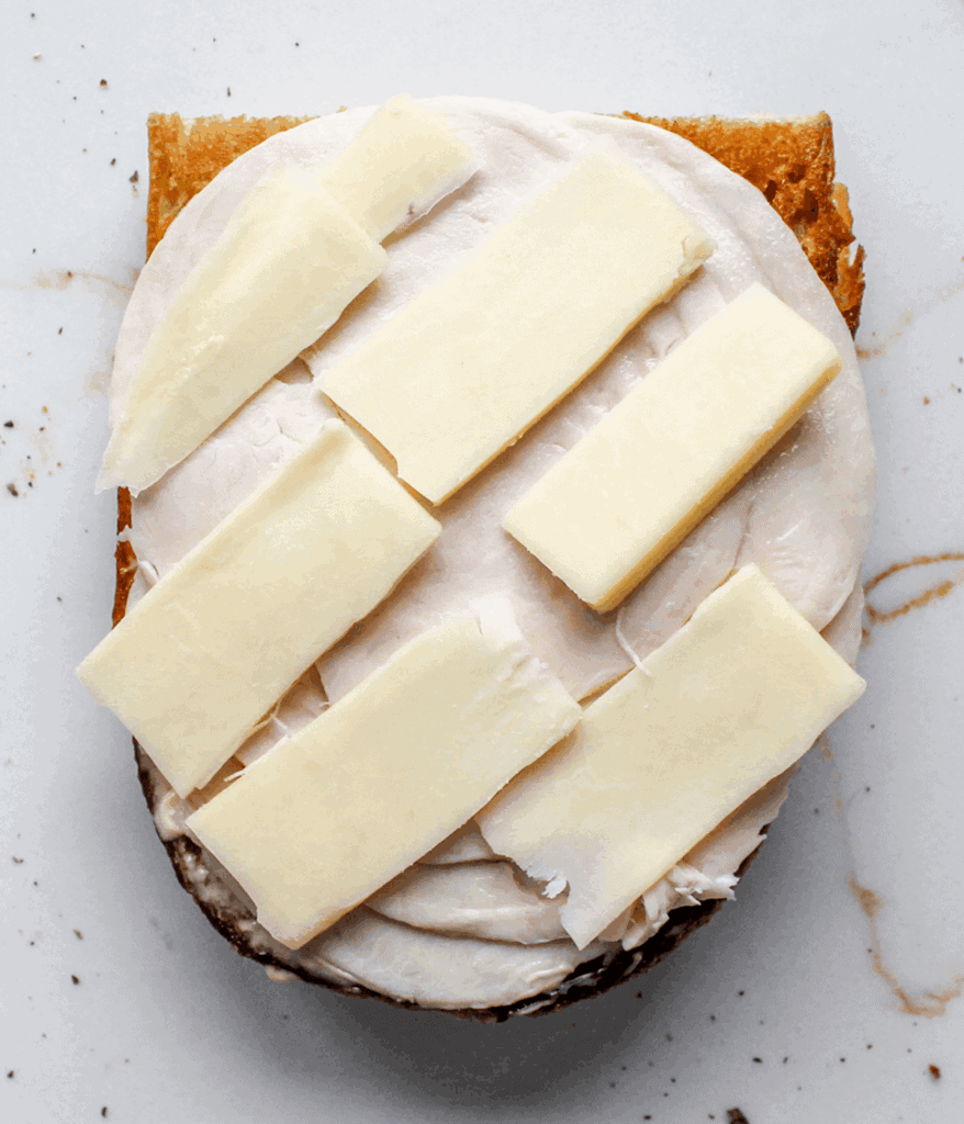 cheese and turkey on an open turkey grinder sandwich